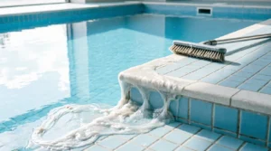 White biofilm buildup on pool tile edge near brush