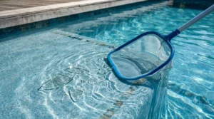 Blue skimmer net scooping broken glass shards from pool