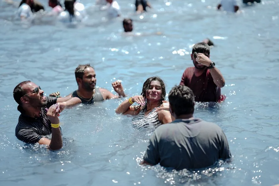 Group of people having fun in a sunny outdoor pool. Perfect summer vacation vibe.