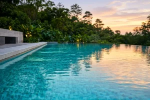 Backyard infinity pool with clear blue water glowing at sunset
