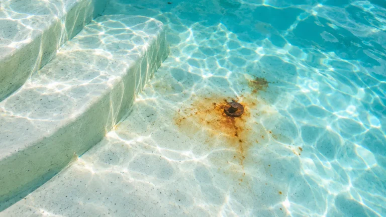 Rust stains surround a metal object on pool plaster